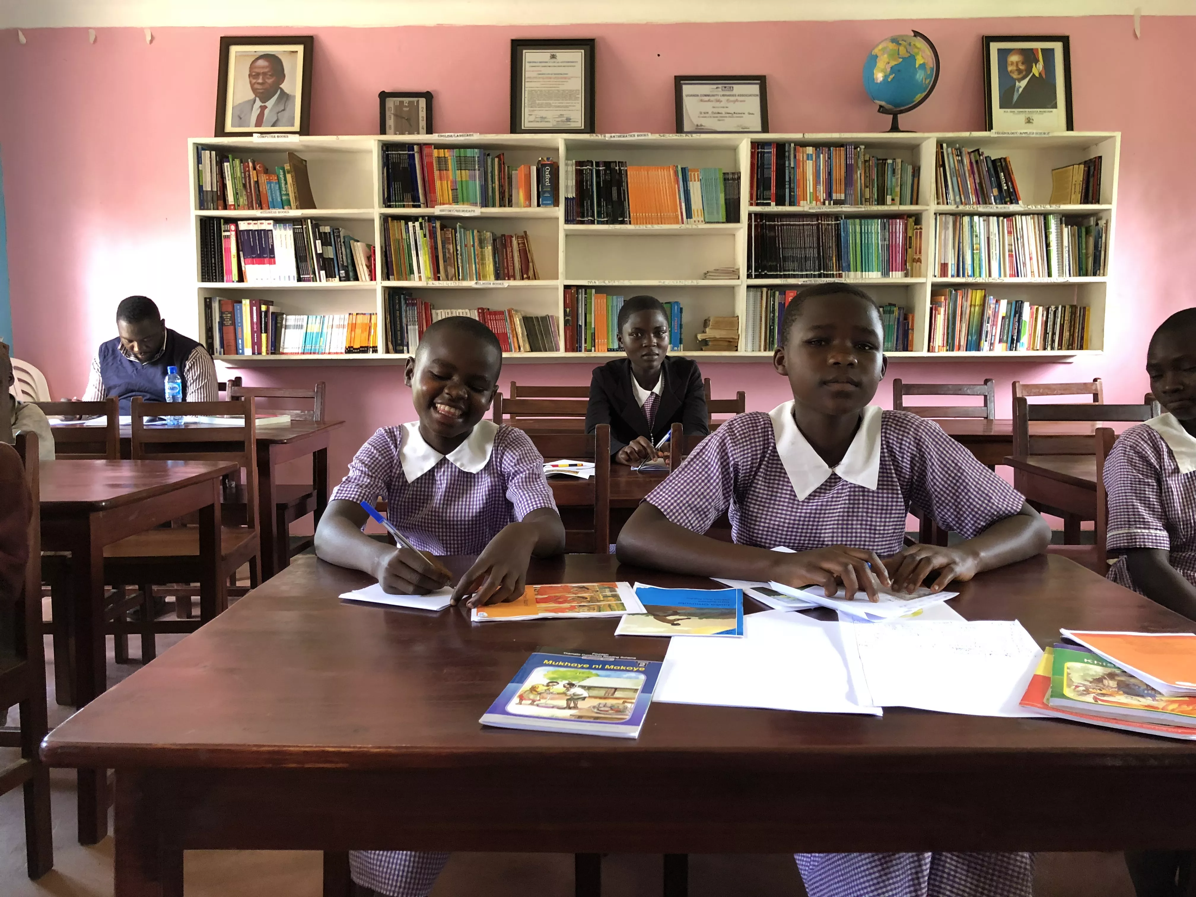 School children sit at a desk in a community library in Uganda